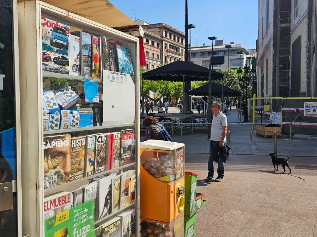 Vista lateral de Kiosco Quim en Plaça Mossèn Homar, con el Ayuntamiento de L’Hospitalet y zona peatonal de alto tránsito